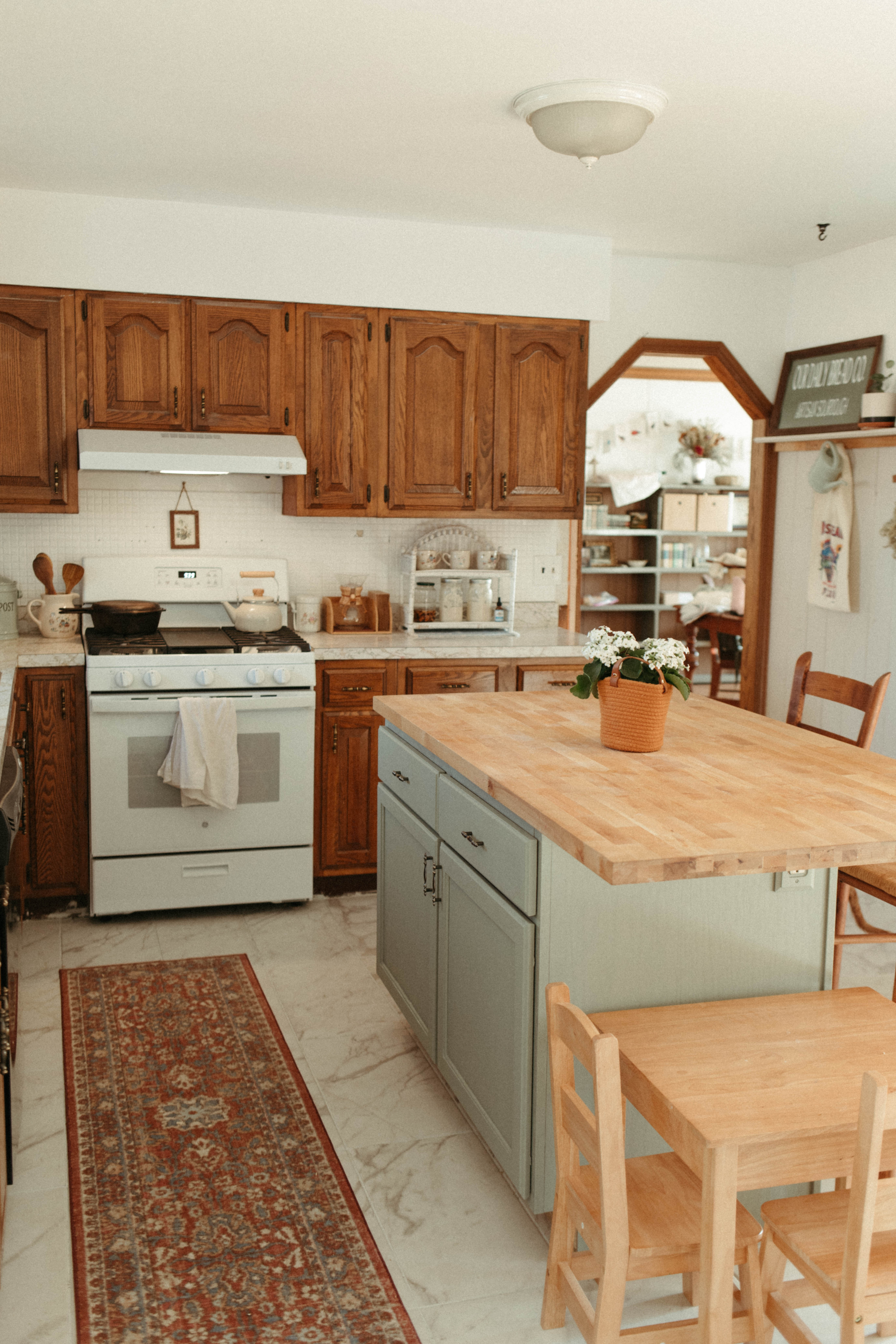 Kitchen with children's wooden table and green island with butcher block counter top.